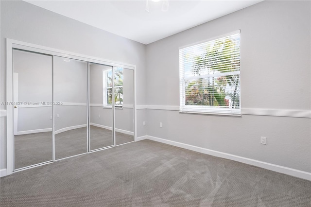 unfurnished bedroom with carpet, a closet, and baseboards