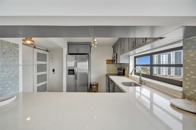 6820 Indian Creek Dr Unit 9A, Miami Beach, FL 33141 - kitchen with decorative backsplash, light countertops, appliances with stainless steel finishes, a sink, and gray cabinets