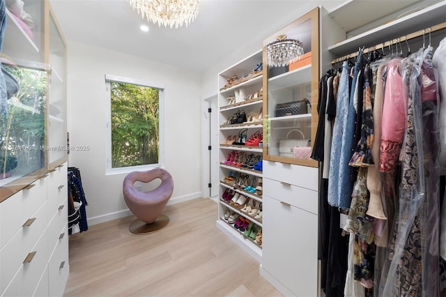 walk in closet featuring a notable chandelier and light wood finished floors