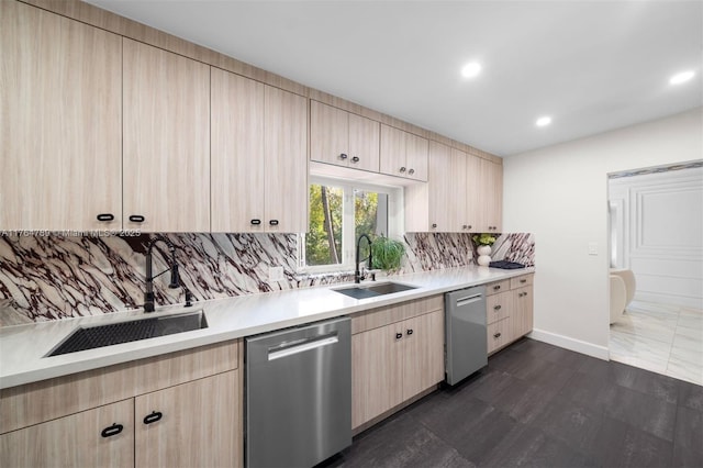 kitchen with light countertops, backsplash, a sink, stainless steel dishwasher, and light brown cabinets