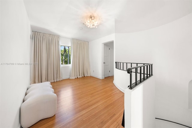 sitting room featuring baseboards, light wood-type flooring, and an upstairs landing