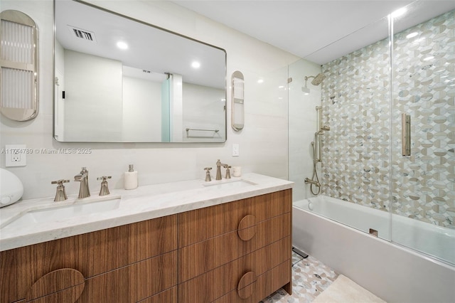 full bath featuring a sink, visible vents, double vanity, and shower / bath combination with glass door