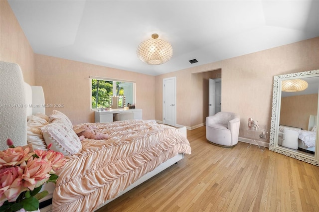 bedroom with baseboards, visible vents, a chandelier, and light wood-type flooring