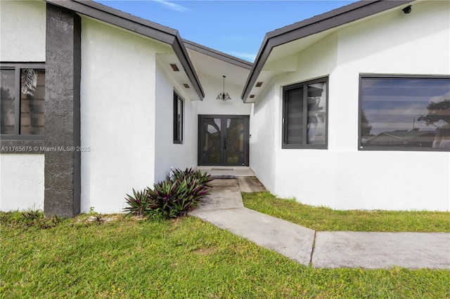 18650 SW 127th Ct, Miami, FL 33177 - property entrance with stucco siding, a lawn, and a surveillance system