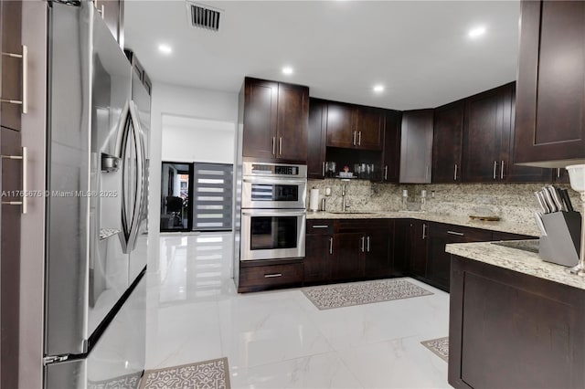 18650 SW 127th Ct, Miami, FL 33177 - kitchen with appliances with stainless steel finishes, decorative backsplash, dark brown cabinets, light stone countertops, and recessed lighting