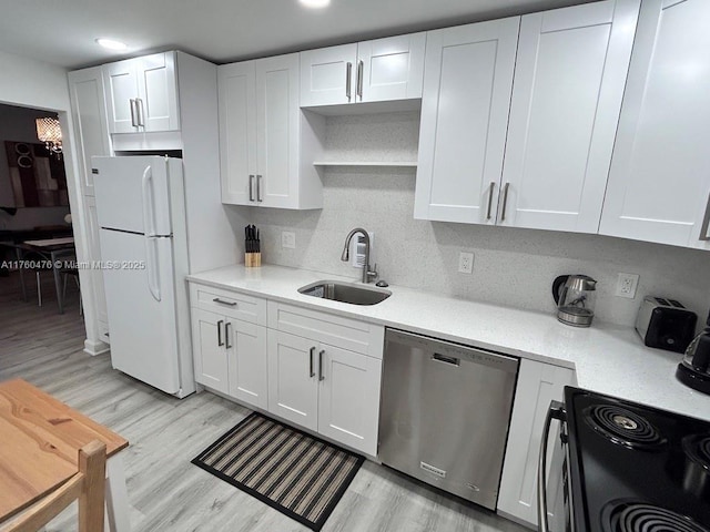 kitchen with freestanding refrigerator, a sink, white cabinets, dishwasher, and light wood-type flooring