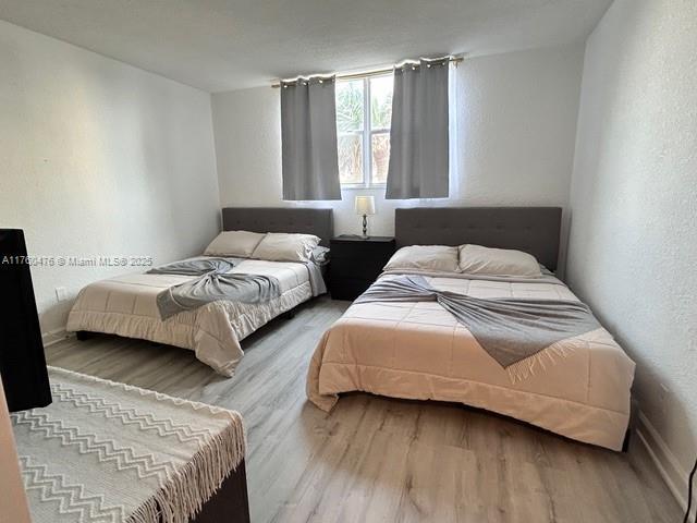 bedroom with wood finished floors and a textured wall