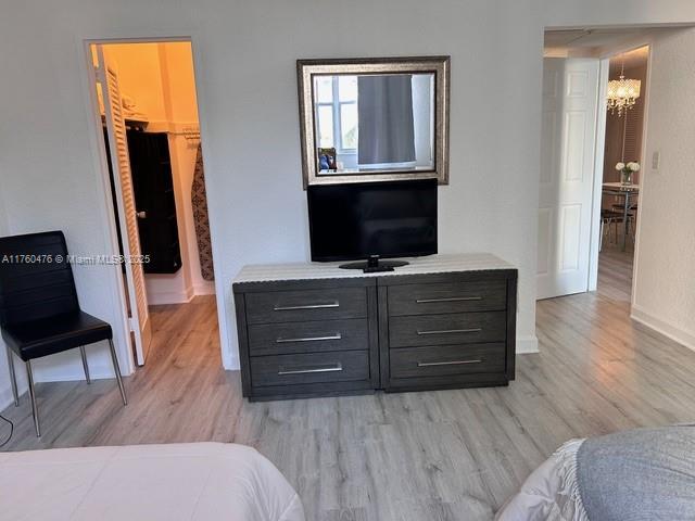 bedroom featuring a notable chandelier, light wood-type flooring, and baseboards