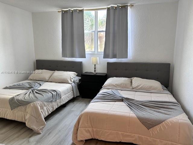 bedroom with wood finished floors and a textured wall