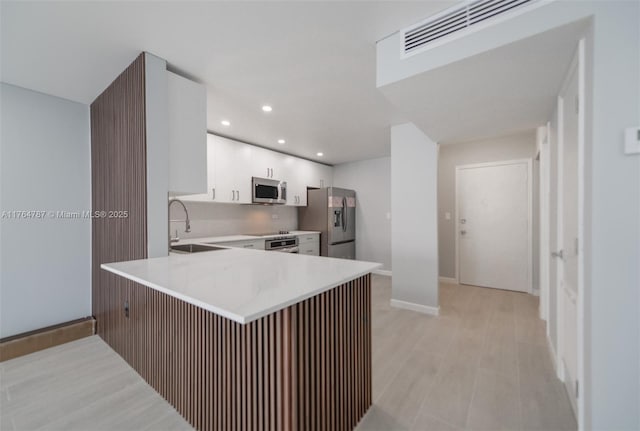 1710 NE 191st St Unit 315-3, Miami, FL 33179 - kitchen featuring a sink, white cabinetry, stainless steel appliances, a peninsula, and light countertops