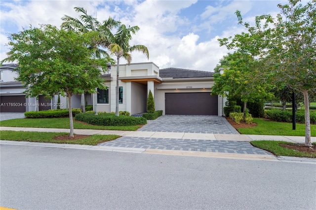 view of front of home with a garage, stucco siding, a front lawn, and decorative driveway