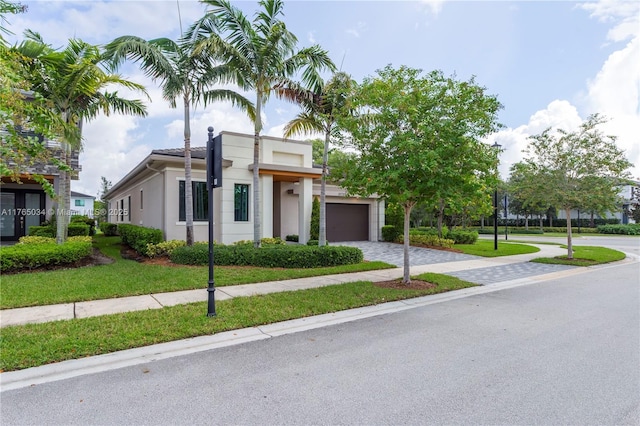 view of front of property with a garage, stucco siding, driveway, and a front yard