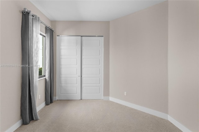 unfurnished bedroom with baseboards, a closet, and light colored carpet