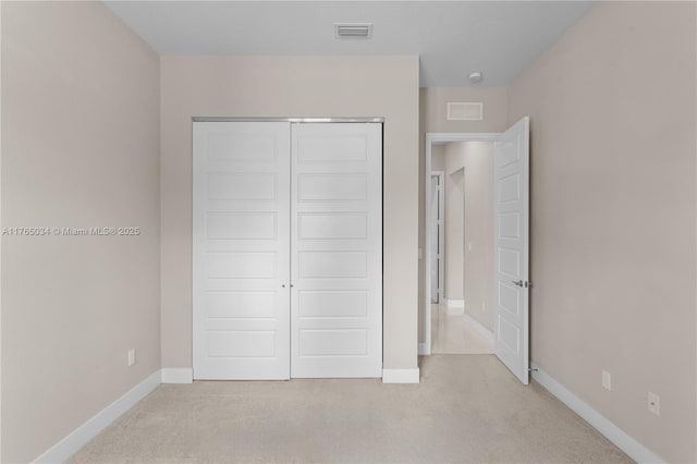 unfurnished bedroom featuring baseboards, light carpet, a closet, and visible vents