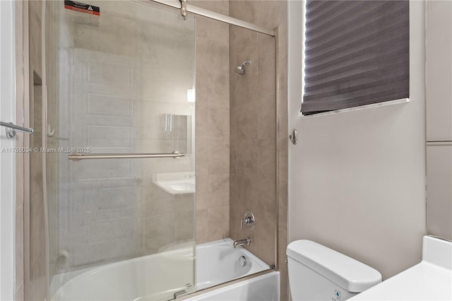 bathroom featuring toilet and bath / shower combo with glass door