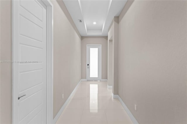 corridor featuring baseboards, light tile patterned floors, and visible vents