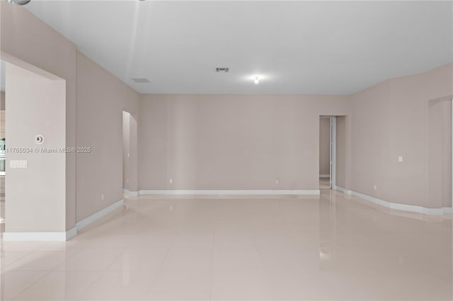 empty room featuring light tile patterned floors, baseboards, and visible vents