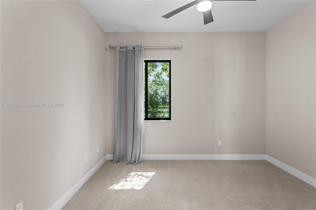 empty room featuring baseboards, ceiling fan, and light carpet