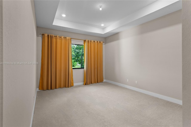 carpeted spare room with baseboards, a tray ceiling, and recessed lighting