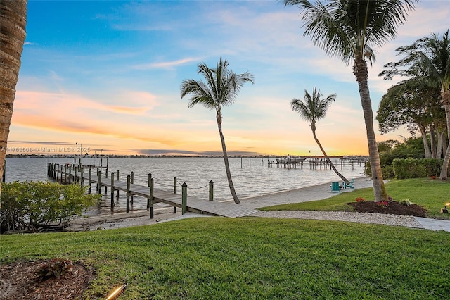 view of dock featuring a lawn and a water view