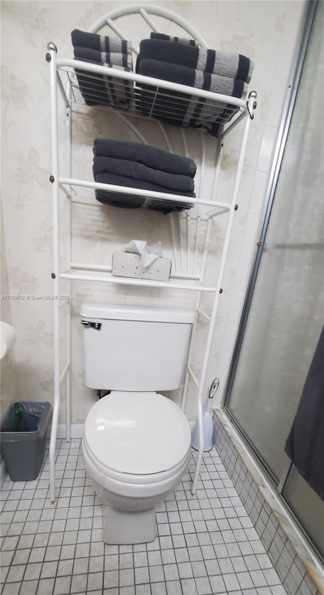 bathroom with tile patterned flooring, toilet, and a stall shower