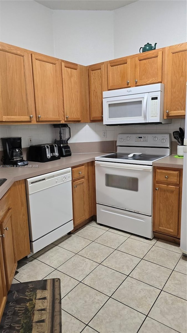 1013 Park Ridge Cir, Kissimmee, FL 34746 - kitchen featuring brown cabinets, backsplash, white appliances, light countertops, and light tile patterned floors