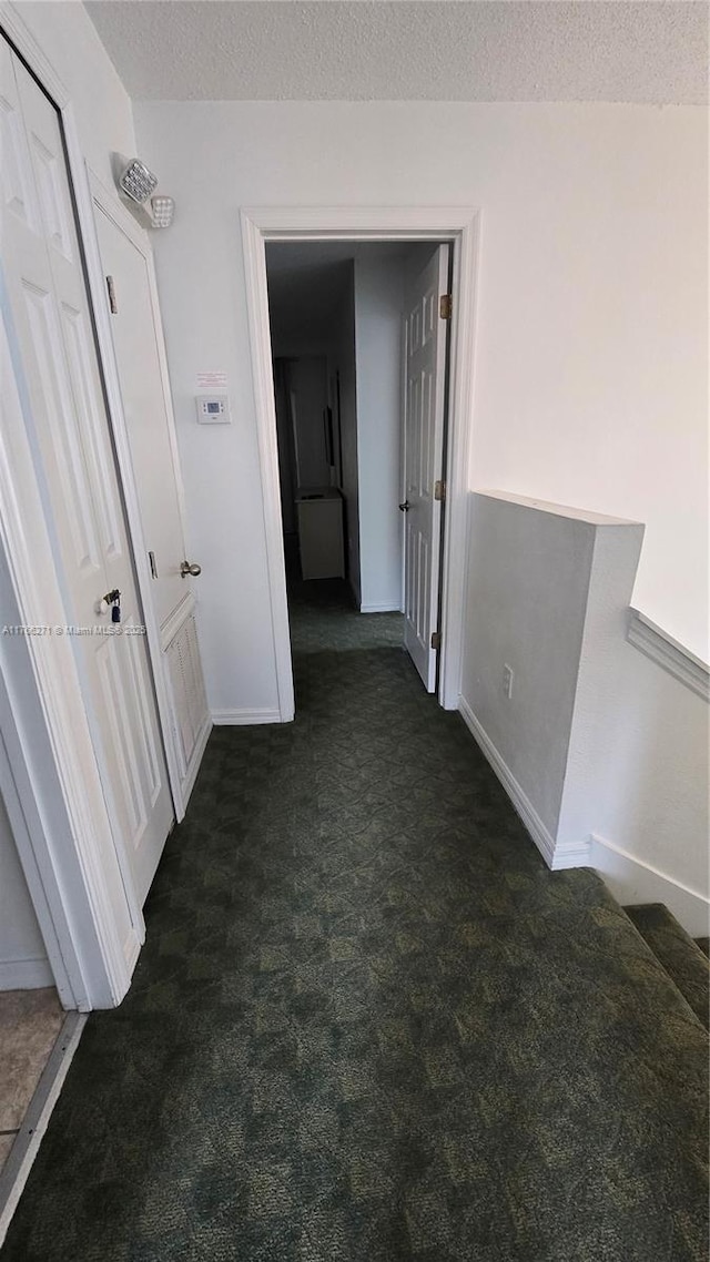 1013 Park Ridge Cir, Kissimmee, FL 34746 - hallway featuring baseboards, dark colored carpet, and a textured ceiling