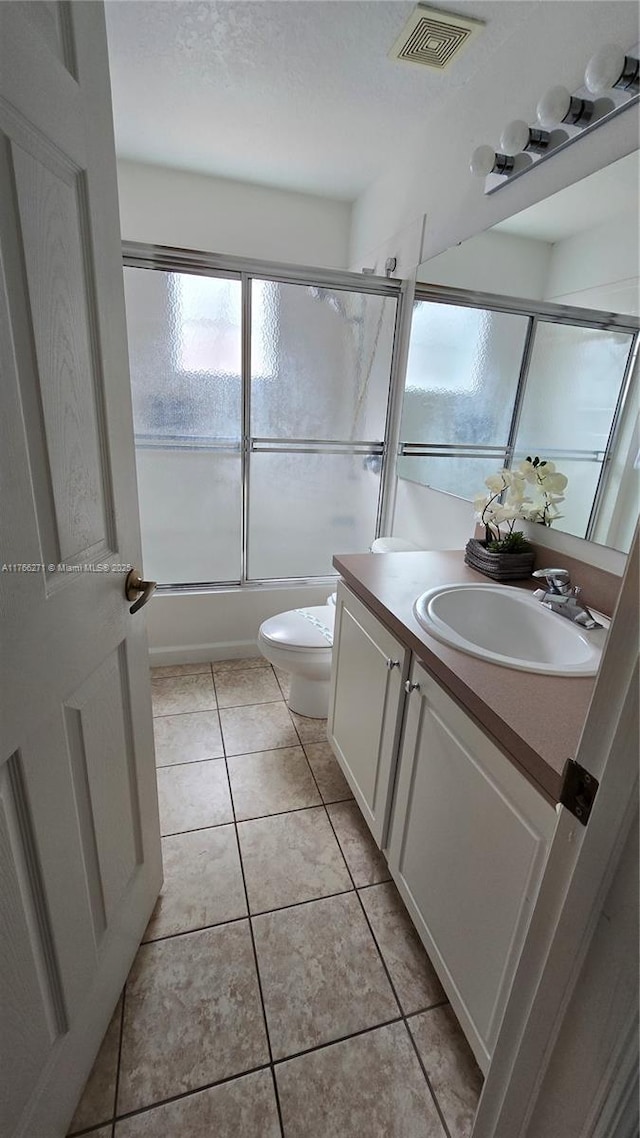 1013 Park Ridge Cir, Kissimmee, FL 34746 - full bath with visible vents, toilet, tile patterned flooring, bath / shower combo with glass door, and vanity