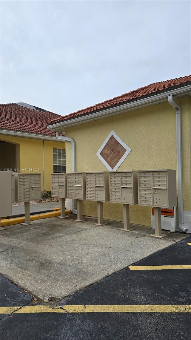 1013 Park Ridge Cir, Kissimmee, FL 34746 - view of home's exterior featuring covered and uncovered parking, mail area, a tiled roof, and stucco siding