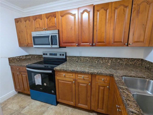 kitchen with a sink, stainless steel microwave, brown cabinetry, and range with electric cooktop