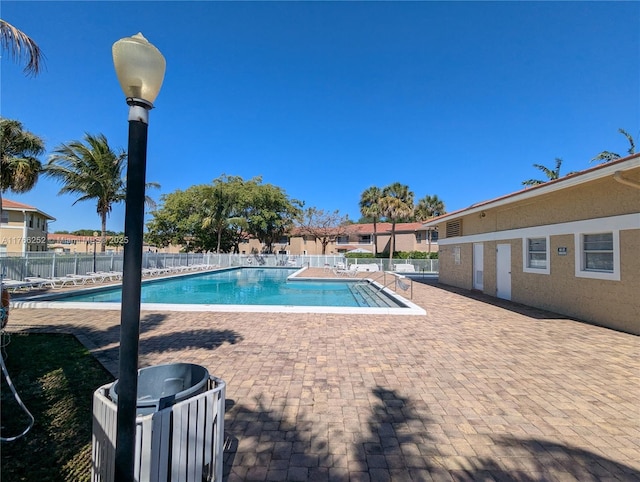 community pool with a patio area and fence