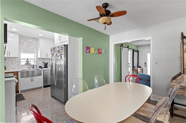 5233 NE 4th Ave, Oakland Park, FL 33334 - dining area with light speckled floor, a ceiling fan, a barn door, and a textured ceiling