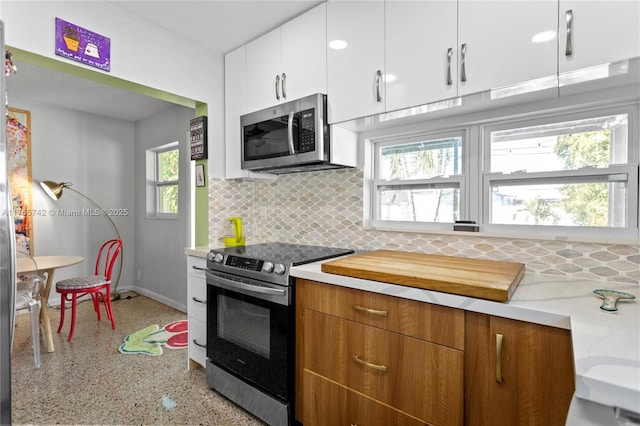 5233 NE 4th Ave, Oakland Park, FL 33334 - kitchen featuring white cabinetry, light countertops, tasteful backsplash, stainless steel appliances, and speckled floor
