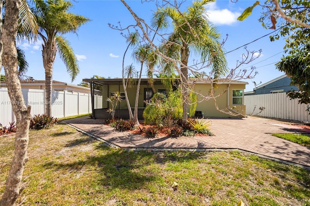 5233 NE 4th Ave, Oakland Park, FL 33334 - rear view of property featuring a sunroom, stucco siding, fence, a yard, and a patio area