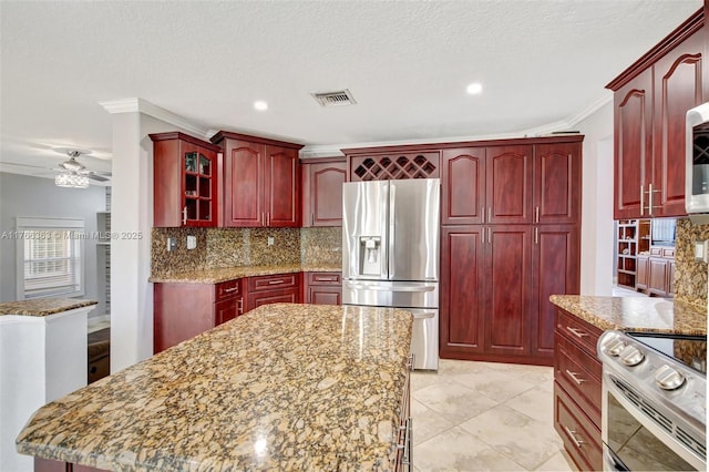 15852 SW 14th St, Pembroke Pines, FL 33027 - kitchen with stainless steel appliances, reddish brown cabinets, ornamental molding, tasteful backsplash, and light stone counters