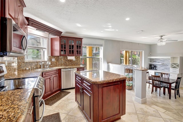 15852 SW 14th St, Pembroke Pines, FL 33027 - kitchen featuring appliances with stainless steel finishes, reddish brown cabinets, plenty of natural light, tasteful backsplash, and ornamental molding