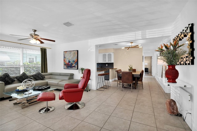 living area with visible vents, light tile patterned flooring, and ceiling fan with notable chandelier