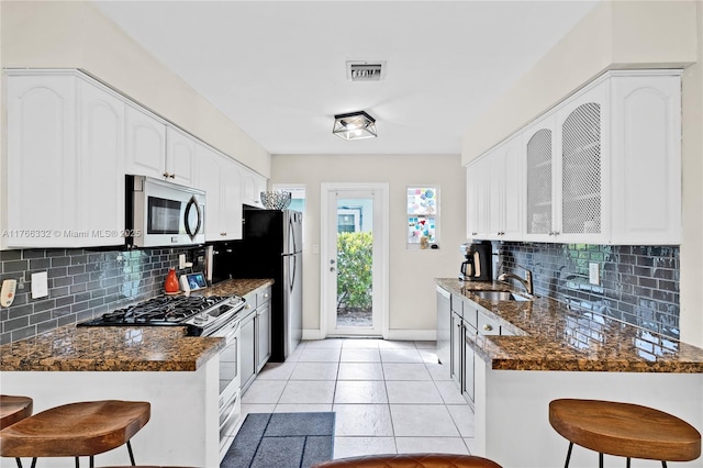 kitchen with a breakfast bar area, baseboards, visible vents, a sink, and appliances with stainless steel finishes