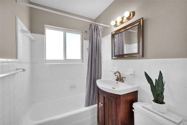 full bath with a sink, tile walls, toilet, a wainscoted wall, and shower / tub combo