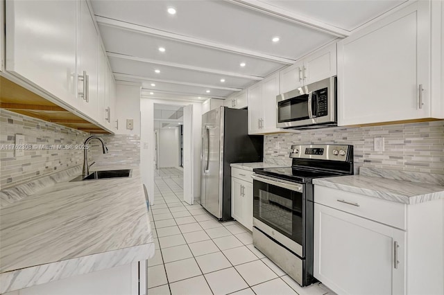 4000 Towerside Ter Unit 302, Miami, FL 33138 - kitchen featuring stainless steel appliances, a sink, backsplash, light tile patterned floors, and white cabinets