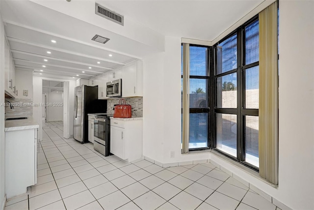 4000 Towerside Ter Unit 302, Miami, FL 33138 - kitchen with stainless steel appliances, decorative backsplash, light tile patterned floors, light countertops, and recessed lighting