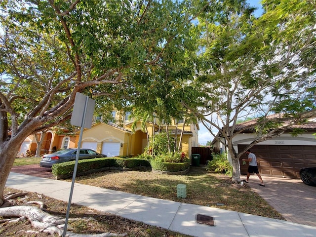 11009 NW 80th Ln, Doral, FL 33178 - view of property hidden behind natural elements featuring a garage, driveway, and stucco siding