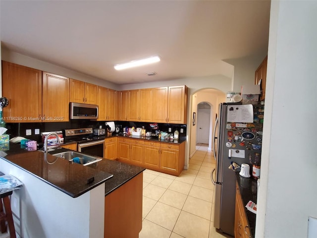 11009 NW 80th Ln, Doral, FL 33178 - kitchen with appliances with stainless steel finishes, arched walkways, a peninsula, light tile patterned floors, and a breakfast bar area