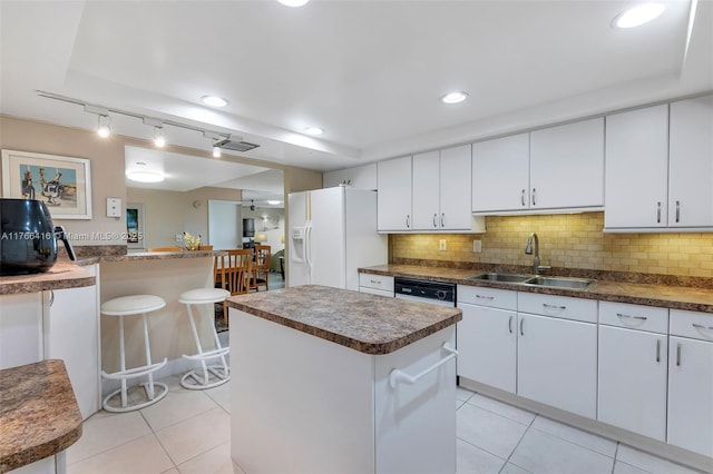 kitchen featuring a sink, backsplash, a kitchen island, white fridge with ice dispenser, and light tile patterned floors