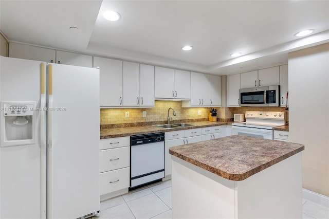 kitchen with light tile patterned floors, decorative backsplash, white appliances, and a sink