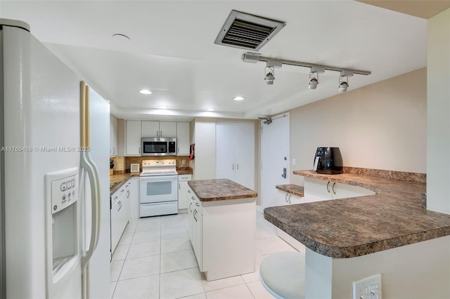 kitchen featuring visible vents, a center island, light tile patterned floors, decorative backsplash, and white appliances