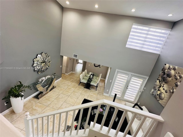 stairs featuring a high ceiling, plenty of natural light, baseboards, and visible vents
