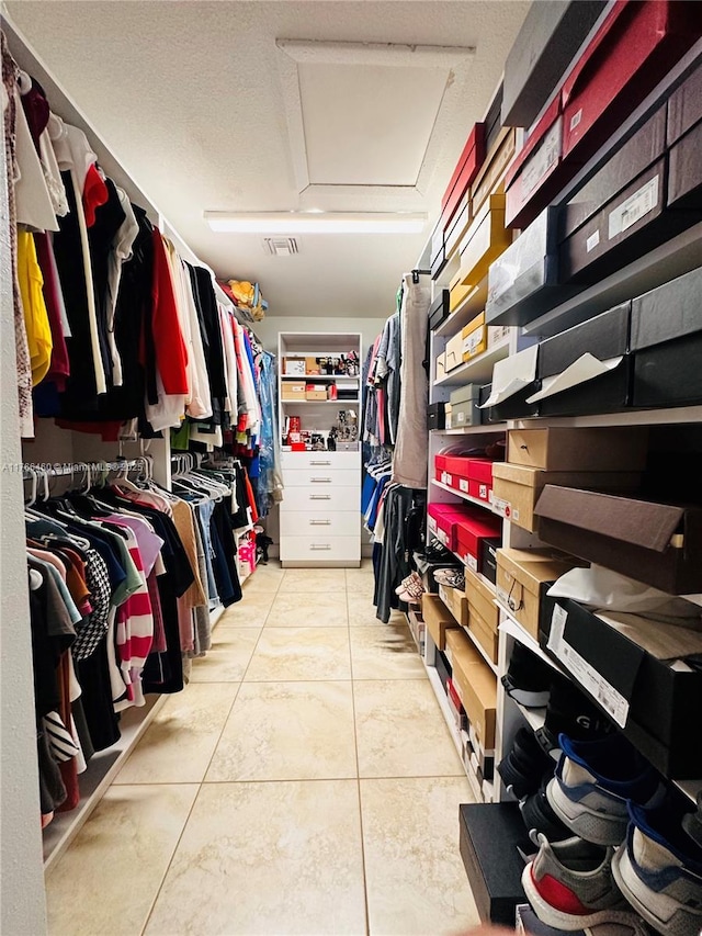 walk in closet featuring attic access and light tile patterned flooring