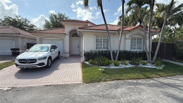 mediterranean / spanish home with stucco siding, decorative driveway, an attached garage, and a tile roof