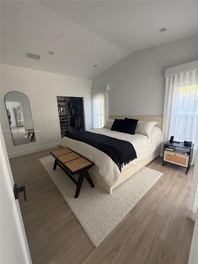 bedroom featuring light wood-style flooring, visible vents, and lofted ceiling